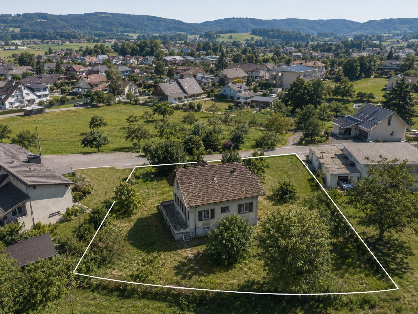 Luftaufnahme einer Parzelle mit weiss eingezeichneter Grenze: ein &auml;lteres Wohnhaus auf grossz&uuml;giger Wiese