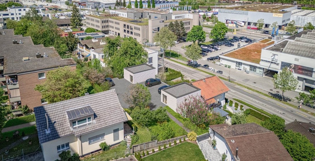 Luftaufnahme der Umgebung: das Doppelhaus im Quartier, dahinter Strasse und Gewerbebauten