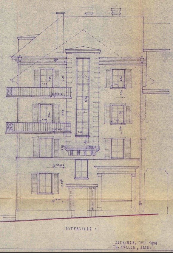Bauzeichnung der Ostfassade in blauer Tinte auf vergilbtem Papier: viergeschossiges Haus mit Balkonen, Fensterl&auml;den und eingetragenen Massen